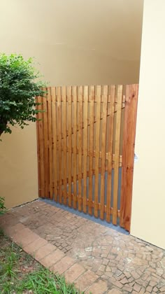 a wooden gate is next to a small tree