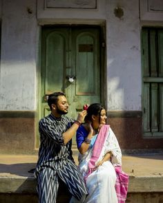 a man and woman sitting on the steps in front of a building, brushing their hair