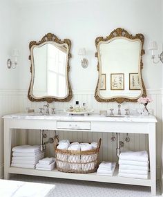 a white bathroom with two mirrors above it