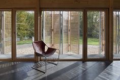 an empty room with large windows and a chair on the floor in front of it