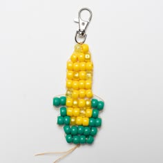 a corn on the cob keychain with green and yellow beads hanging from it