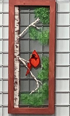 a red bird sitting on top of a wooden frame