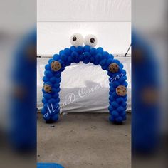 an arch made out of blue balloons with cookies on it and eyes in the middle