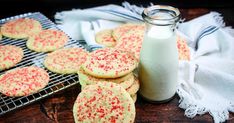 some cookies and a bottle of milk on a cooling rack next to a wooden table