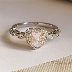 a heart shaped diamond ring on top of a table