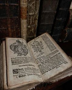 an open book sitting on top of a wooden table next to two old books with writing on them