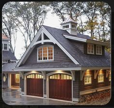 a two car garage with lights on the windows and an attached dormer above it