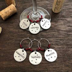 wine glass charms with sayings on them sitting next to some corks and bottles