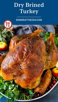 a roasted turkey on a platter with apples and cranberries in the background