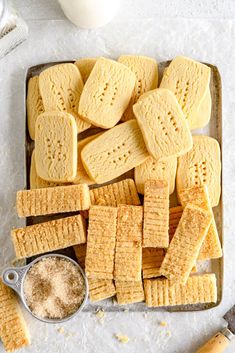 a tray filled with shortbread crackers next to a bottle of milk and two spoons