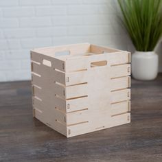 a wooden crate sitting on top of a table next to a potted plant