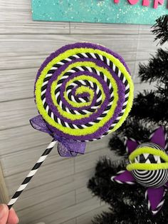 a purple and green lollipop on a stick next to a christmas tree