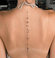 the back of a woman's neck with an intricate tattoo design on her lower back