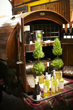 several bottles of wine sit in front of an open trunk on a table with other items