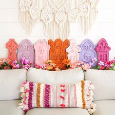 a couch with pillows and flowers in front of a wall hanging on the wall behind it