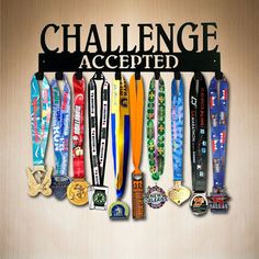 a sign that says challenge accepted with many medals hanging from it's sides on a wall