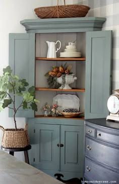 an old china cabinet is painted green and decorated with wicker baskets on the top