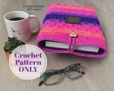 a crochet book bag sitting on top of a table next to a cup of coffee