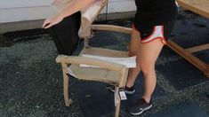 a woman standing next to a wooden table with a chair on it's legs