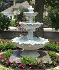 a water fountain in the middle of a flower garden