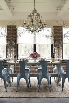 a dining room table with blue chairs and a chandelier hanging from the ceiling