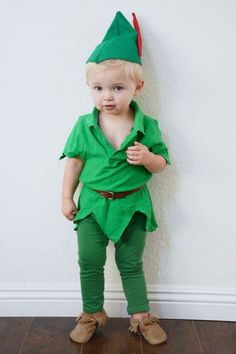 a little boy dressed up in a green outfit