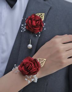 a man in a tuxedo with two red roses on his lapel and pearl bracelets