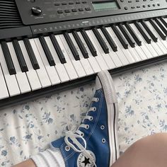 a person wearing converse shoes sitting in front of an electronic keyboard