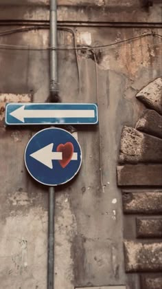 two blue and white street signs with an arrow pointing in opposite directions on a brick wall