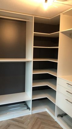 an empty walk in closet with white shelving and black wall mounted shelves on both sides