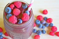 a jar filled with blueberries and raspberries on top of a table