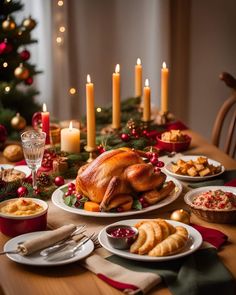 a table is set for christmas dinner with turkey and other foods on it, candles in the background