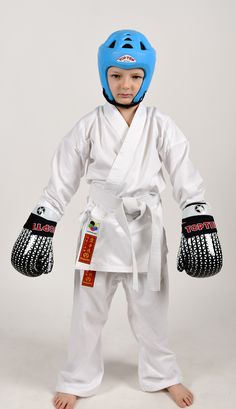 a young boy in a blue helmet and white karate outfit standing with his hands on his hips