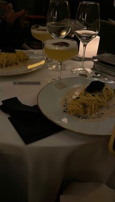 two glasses of wine are sitting on a table with pasta and cheese in front of them