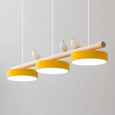 three birds sitting on top of a light fixture with yellow tape hanging from the ceiling