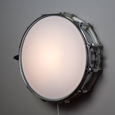 a drum head mounted to the wall with a light on it's side,