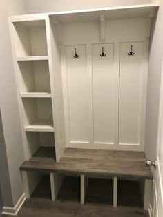 an empty white mud room with benches and shelves