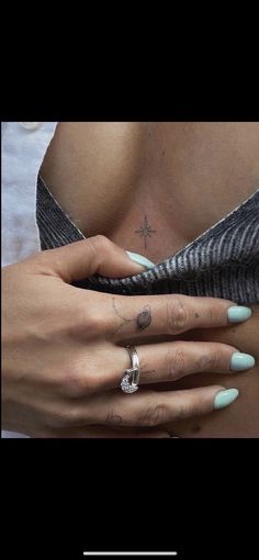 a woman's stomach with two rings on her left hand and a cross tattoo on her right arm