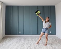 a woman holding a drill and a tool in her hand while standing on the floor