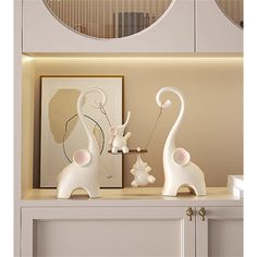 two white elephant figurines sitting on top of a shelf next to a mirror