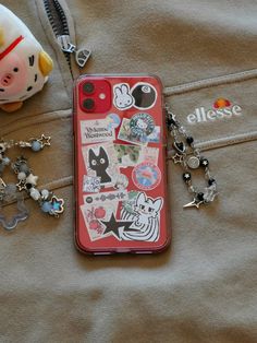 an iphone case with many stickers on it next to a key chain and charm