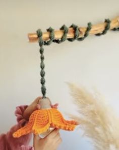 a person holding a small toy in front of a string with an orange bird on it