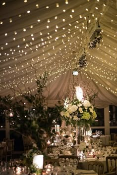 the inside of a tent with tables and chairs set up for a wedding reception at night