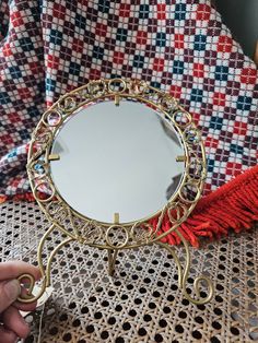 a person is holding a small mirror on a table next to a red and blue blanket