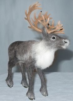 a stuffed deer with antlers on it's head is standing in front of a gray background