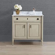 a white sink sitting on top of a wooden cabinet next to a vase with flowers