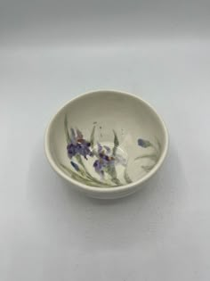 a white bowl with purple flowers painted on it