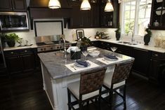 a large kitchen with an island in the middle and two bar stools at the end