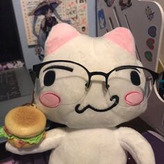 a stuffed cat with glasses holding a hamburger