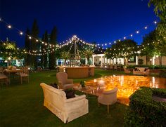 an outdoor seating area at night with string lights strung across the lawn and tables set up for dinner